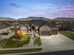 French provincial home with a garage, a residential view, concrete driveway, stone siding, and a mountain view