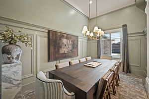 Dining room featuring a decorative wall, a high ceiling, a chandelier, and wood finished floors