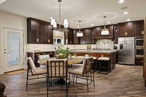 Kitchen featuring dark brown cabinets, decorative backsplash, appliances with stainless steel finishes, pendant lighting, and recessed lighting
