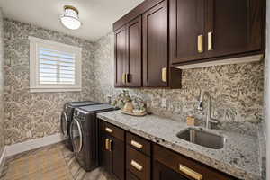 Laundry area featuring washer and dryer, cabinet space, and wallpapered walls