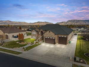 French country style house with a garage, driveway, a mountain view, and stone siding