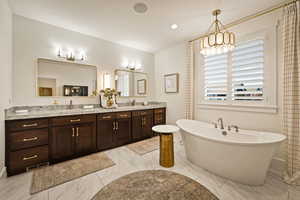 Full bathroom with double vanity, a freestanding tub, recessed lighting, and a chandelier