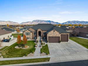 French country home featuring a residential view, a garage, stone siding, and a mountain view