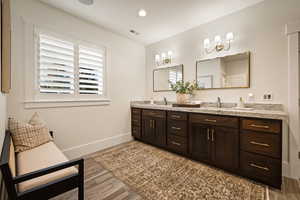 Full bathroom with double vanity, light wood finished floors, and recessed lighting