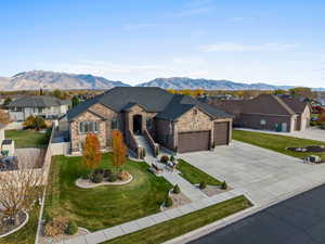 French country style house featuring a mountain view, concrete driveway, a garage, and stone siding