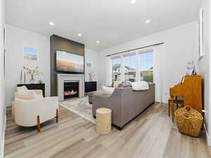 Living area featuring recessed lighting, healthy amount of natural light, a glass covered fireplace, and light wood finished floors
