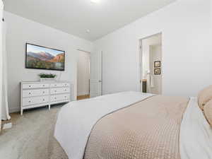 Carpeted bedroom featuring ensuite bathroom and baseboards