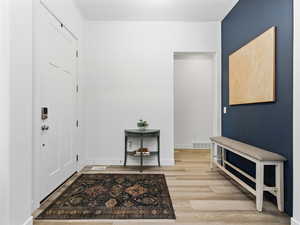Foyer with light wood finished floors and baseboards