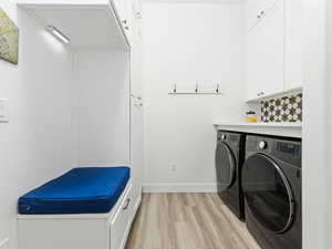 Laundry area with cabinet space, light wood-style floors, and independent washer and dryer