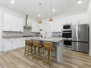 Kitchen featuring appliances with stainless steel finishes, hanging light fixtures, a breakfast bar, white cabinets, and a kitchen island with sink
