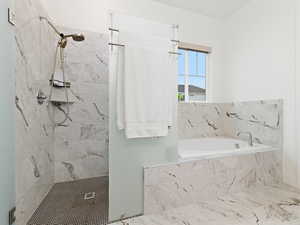 Bathroom with a marble finish shower and a garden tub
