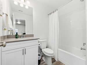 Bathroom with shower / tub combo, vanity, and dark wood-style flooring