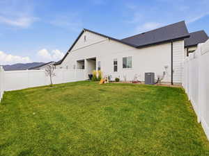 Rear view of house with a fenced backyard, a shingled roof, and a mountain view