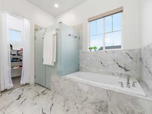 Bathroom with a marble finish shower, a bath, and a spacious closet