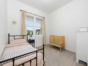 Bedroom featuring light colored carpet and lofted ceiling