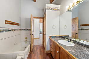 Bathroom #2 featuring a garden tub, vanity, dark wood-style flooring, tile walls, and a towering ceiling