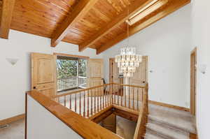 Light, bright upstairs flow. Staircase featuring a chandelier, carpet floors, a wood ceiling with exposed beams, high vaulted ceiling, and a skylight