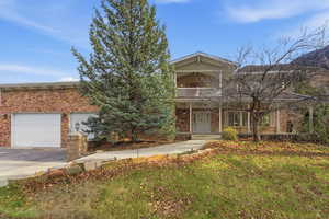 Ground-level front elevation showing porch, balcony & mountain backdrop.