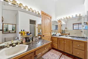Bathroom featuring a shower stall, two vanities, ornamental molding, and dark wood-style floors