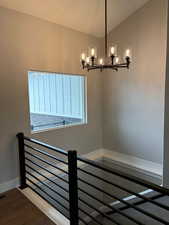 Staircase with a chandelier, and vaulted ceiling