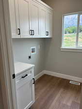 Laundry room with LVP wood-type flooring, custom cabinet space, and washer/dryer hookups