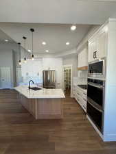 Kitchen with white custom cabinetry, a spacious island, hanging light fixtures, and recessed lighting