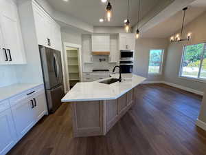Kitchen with tasteful tile backsplash, white cabinetry, light quartz countertops and dining area