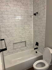 Bathroom with shower / bath combination and toilet - tile extended to ceiling.