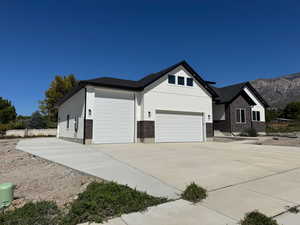 View of side of home featuring brick siding, a 3rd car garage, massive rv pad, concrete driveway, and a mountain view