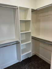 Master bath walk in closet featuring dark carpet