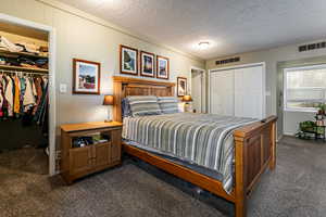 Bedroom featuring dark colored carpet, a textured ceiling, and multiple closets