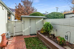View of shed with a fenced backyard and a gate
