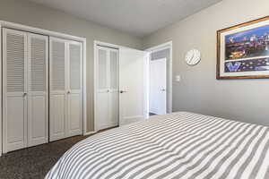 Bedroom featuring a textured ceiling, carpet floors, and two closets