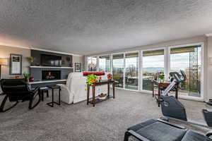 Carpeted living area featuring a textured ceiling, ornamental molding, and a warm lit fireplace