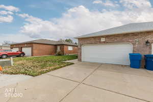 Ranch-style house featuring brick siding, roof with shingles, and concrete driveway