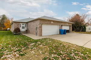 View of front of home featuring a front yard, brick siding, a garage, driveway, and a shingled roof