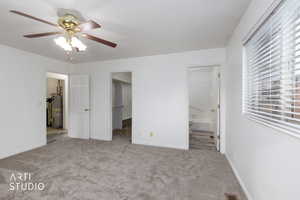 Unfurnished bedroom featuring carpet flooring, a spacious closet, a ceiling fan, water heater, and connected bathroom