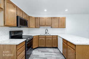Kitchen featuring double oven range, decorative backsplash, light stone countertops, a peninsula, and dishwasher