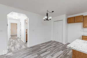 Unfurnished dining area featuring arched walkways, light wood-style floors, and a chandelier