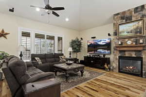 Living area featuring ssolid hardwood hickory flooring, vaulted ceiling, a fireplace, a ceiling fan, and recessed lighting
