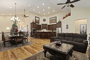 Living area with a ceiling fan,20 ft high vaulted ceiling, arched walkways, a chandelier, and solid hardwood hickory flooring