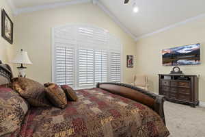 Primary bedroom with ornamental molding, vaulted ceiling, and a ceiling fan