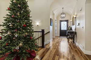 Foyer with solid hardwood hickory flooring, a chandelier, and lofted ceiling