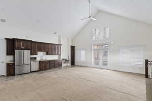 Community Kitchen at clubhouse with high vaulted ceiling, dark brown cabinetry, light countertops, stainless steel appliances, and light colored carpet