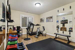 4th bedroom Workout area featuring light wood-style vinyl floors and a textured ceiling all equipment included