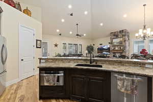 Kitchen with custom knotty alder cabinets, appliances with stainless steel finishes, Granite countertops, a center island with sink, solid hardwood hickory flooring.