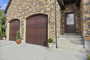 Property entrance featuring stucco and stone siding and driveway