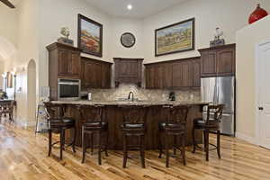 Kitchen with custom knotty alder cabinets, 20 ft towering vaulted ceiling, appliances with stainless steel finishes, Granite countertops, a center island with sink, solid hardwood hickory flooring.