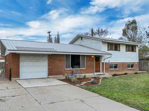 Wide, concrete driveway, brick siding, a new (2017) metal roof, and an attached garage