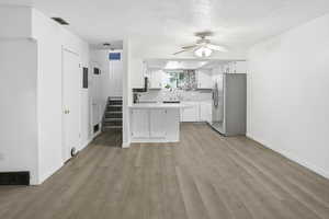 Kitchen with stainless steel appliances, light countertops, white cabinetry, a textured ceiling, and light wood finished floors